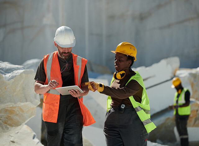 Two workers of factory situated on territory of marble quarry having discussion